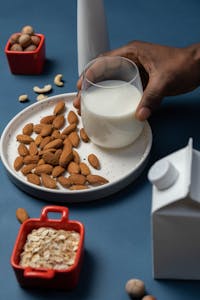 A nutritious setup with almonds, a glass of milk, oats, and nuts on a plate.