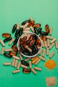 Top view of various colored capsules and powders on a green surface.